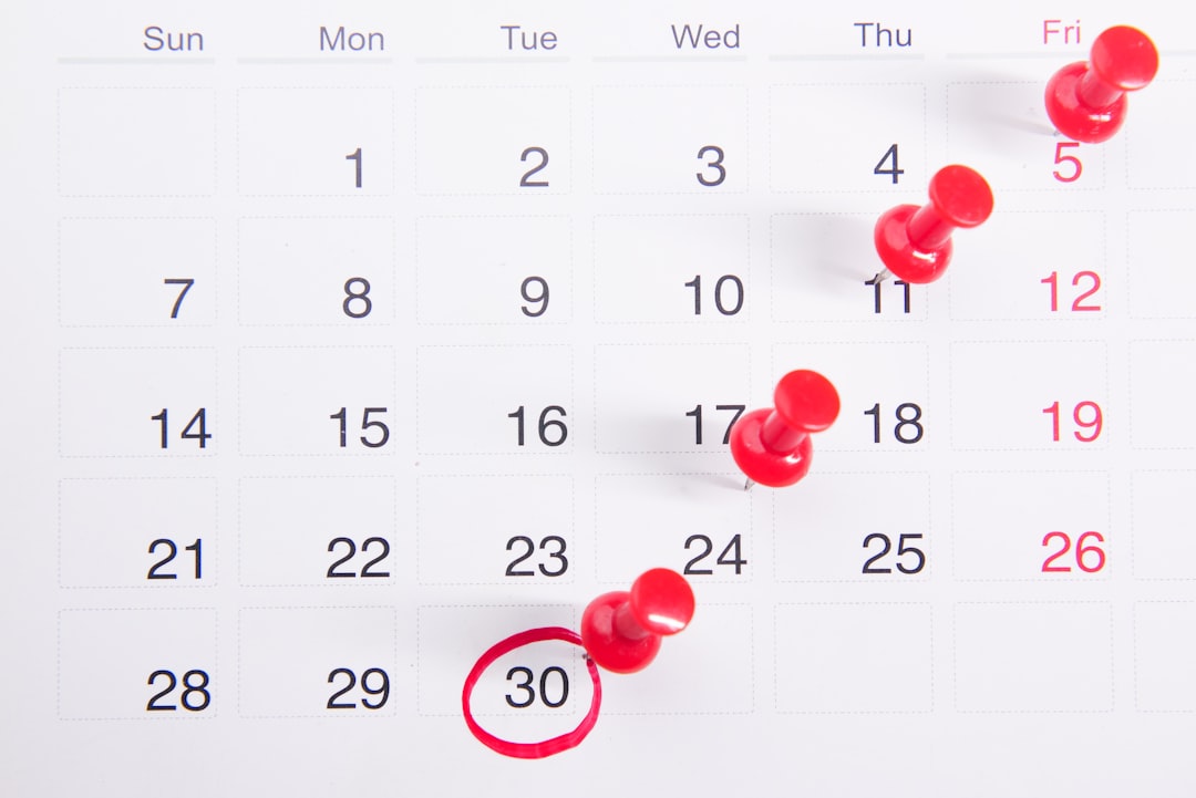 Close-up of a calendar with red pushpins marking important dates