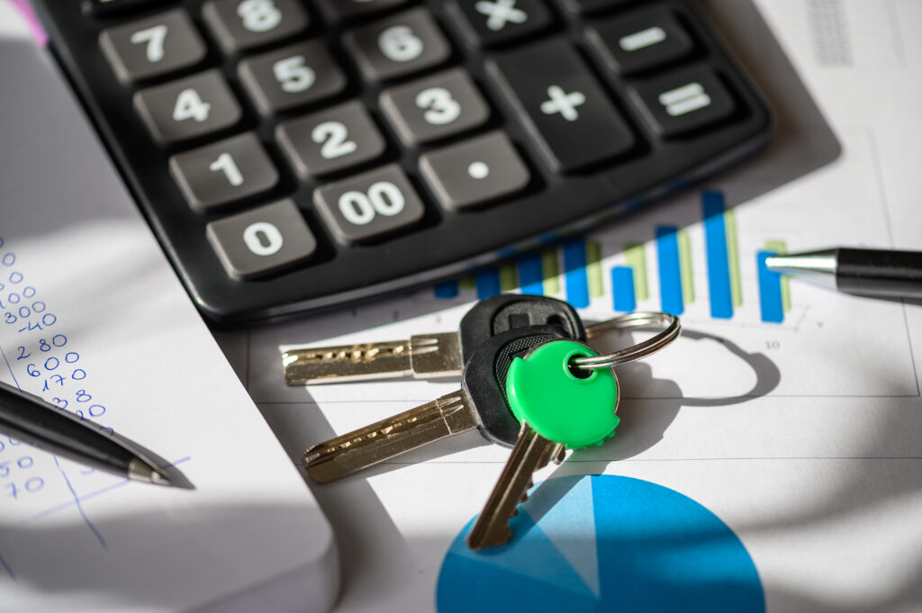 Calculator, keys, and financial documents laid out on a table